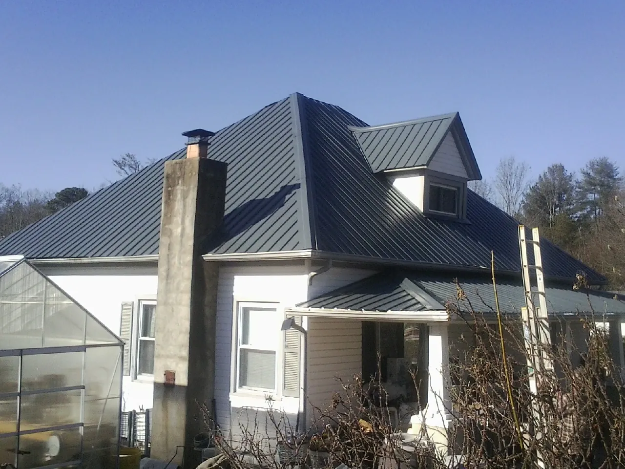 Dark blue standing seam metal roof on a white farmhouse with dormer — Slate & Tile Roof Repair by Roofing Brothers in Estacada