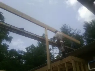 Carpenter setting a ridge beam over a new addition frame — Ice Dam Removal by Roofing Brothers in Estacada