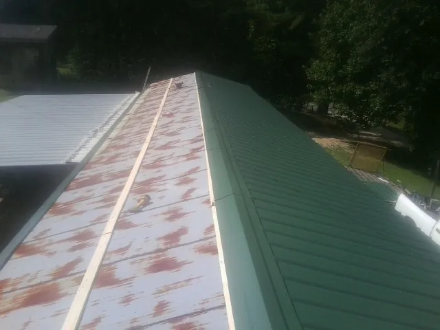 Old rusted panels beside newly installed green metal roofing — Wind Damage Roof Repair by Roofing Brothers in Estacada