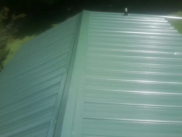 New green metal panels meeting at the ridge of a roof — Flat Roof Repair work by our crew in Estacada