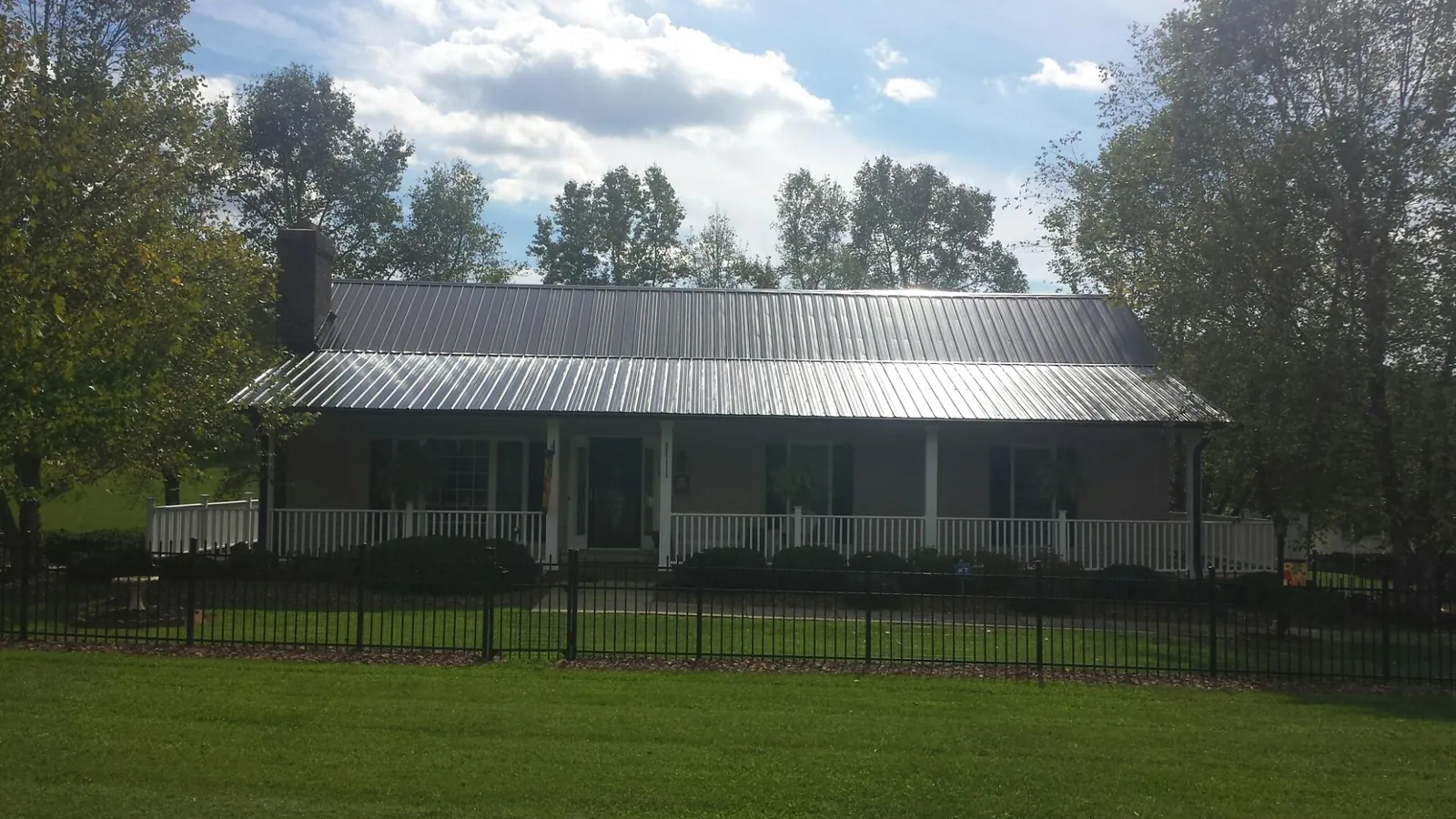 Gray metal roof on a brick ranch with a full width front porch — Gutter Guard Installation work by our crew in Estacada