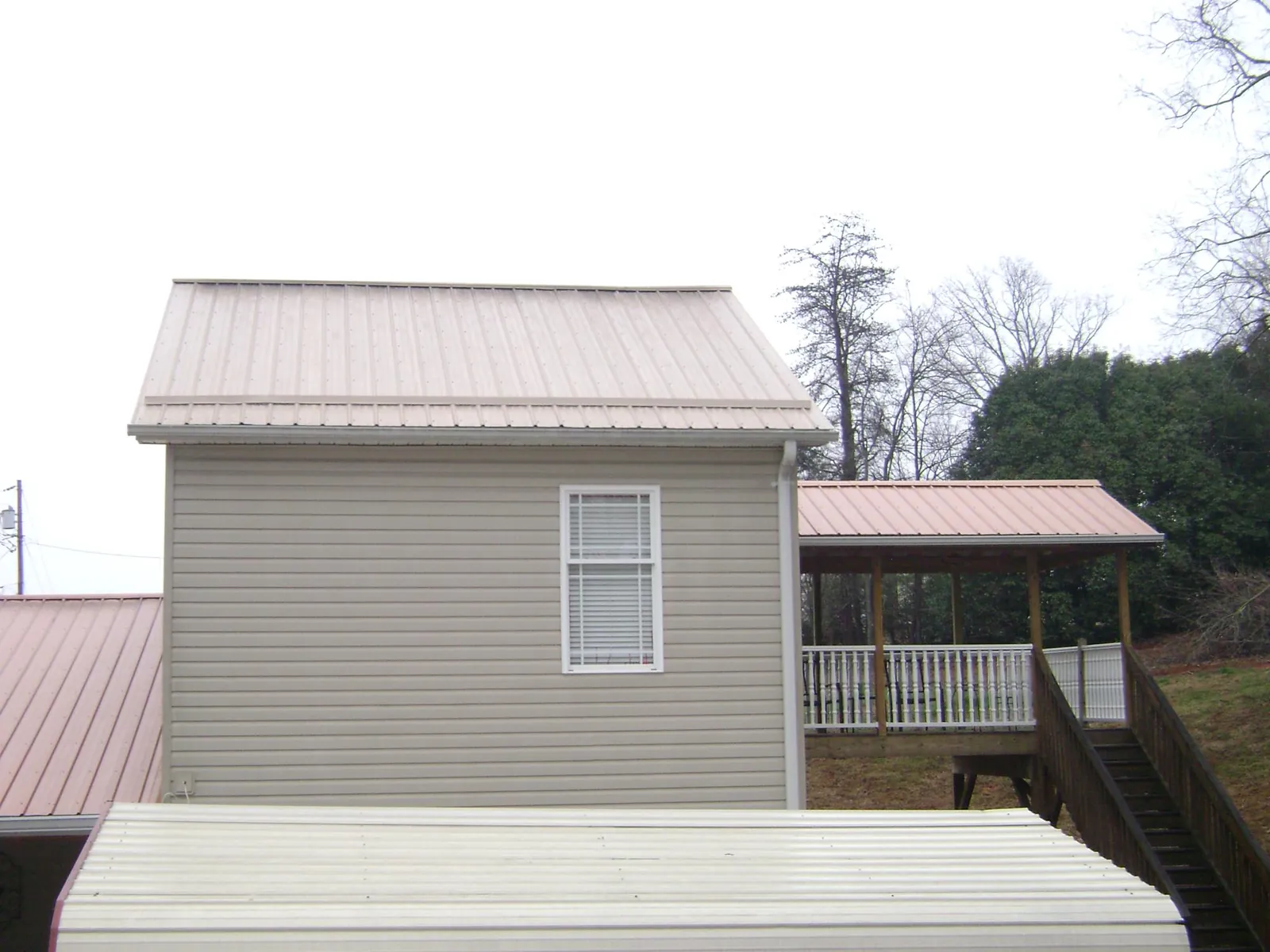 Tan metal roofs on a two story addition and attached porch, from a Roof Replacement job in Estacada
