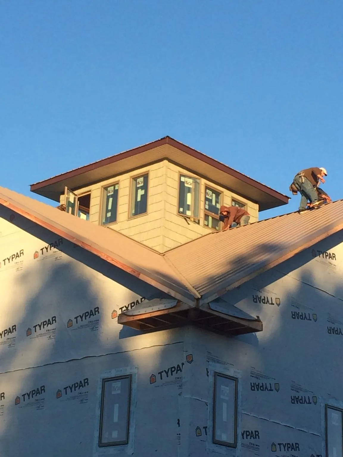Roofers working around a rooftop cupola on a new metal roof at sunset — Roof Waterproofing in Estacada by Roofing Brothers